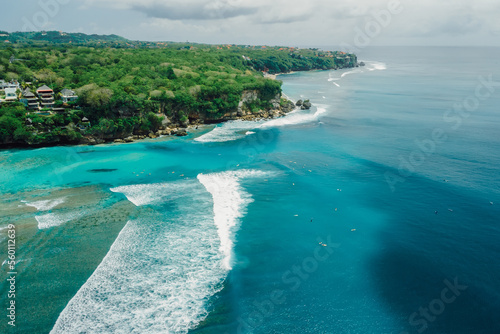 Blue ocean with perfect waves and coastline on Padang Padang surf spot in Bali. Aerial view