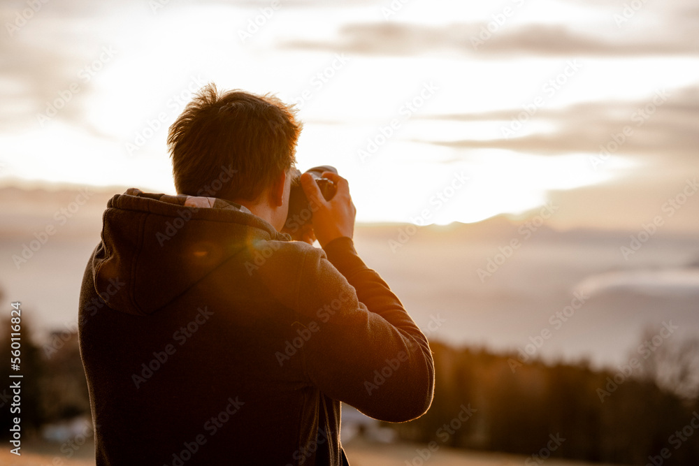 Mann fotografiert bei Sonnenuntergang - obrazy, fototapety, plakaty 