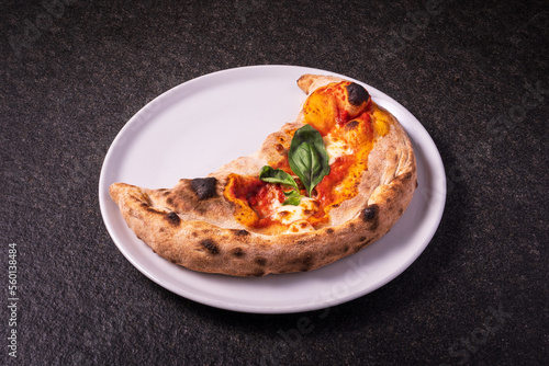 calzone pizza, folded stuffed pizza, italian food on a dark background