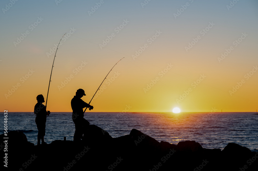 Beautiful sunset over the ocean with two men fishing Beautiful sunset over the ocean with two men fishing