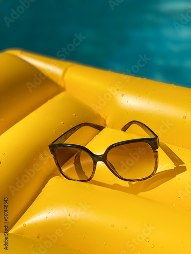 Sunglasses on a yellow floater inside a swimming pool in summer time photo