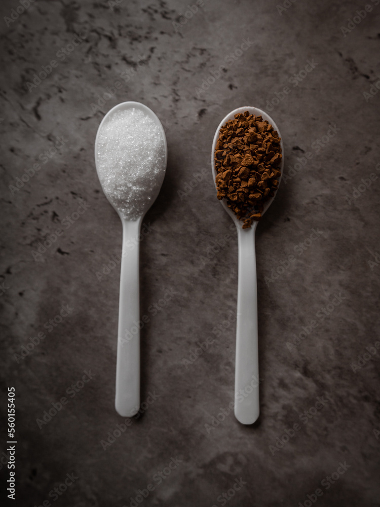 Two spoonfuls of instant coffee and sugar on the kitchen counter in