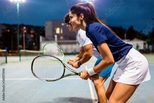 Tennis sport people concept. Mixed doubles player hitting tennis ball with partner standing near net © NDABCREATIVITY