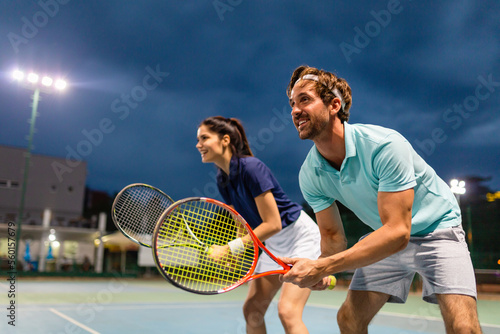 Young couple on tennis court. Handsome man and attractive woman are playing tennis. © NDABCREATIVITY