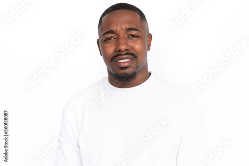 Dissatisfied young man showing irritation. Male African American model with brown eyes, short haircut and beard in white T-shirt making irritated facial expression. Dissatisfaction concept