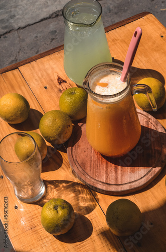 Una jarra de limonada y una jarra de jugo de naranja rodeada de naranjas photo