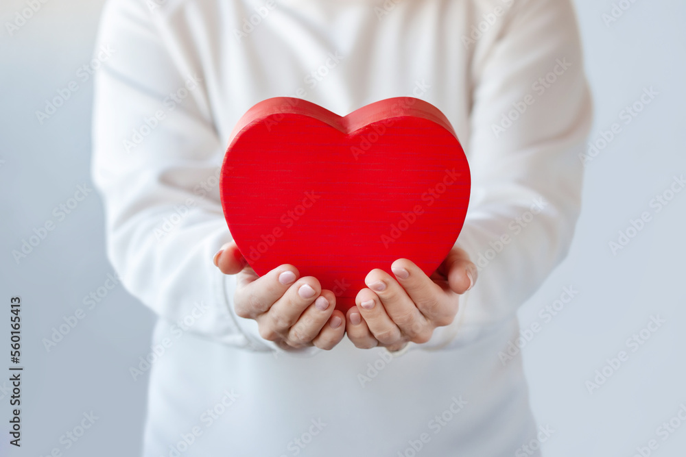 Female hands holding a red heart shaped box. Happy Valentines Day gift box.
