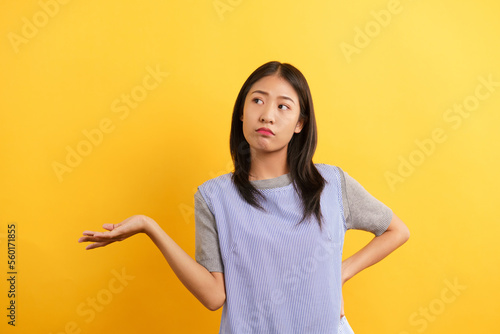 Young women making confused face and open one hand to asking why on isolated yellow background