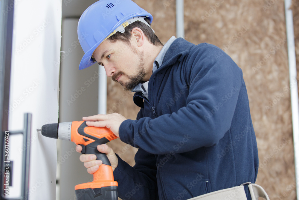 adult builder handyman working with electric drill indoors adult builder handyman working with electric drill indoors