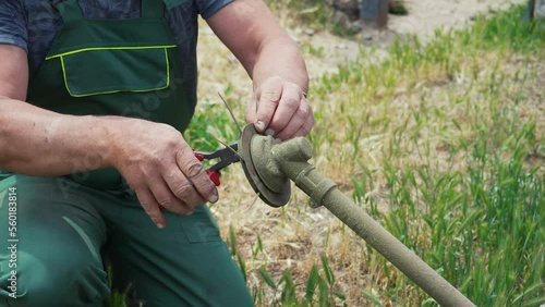 Close-up of a man's hand taking apart a lawn mower to replace parts. Maintains and repairs the weed cutter by replacing parts.