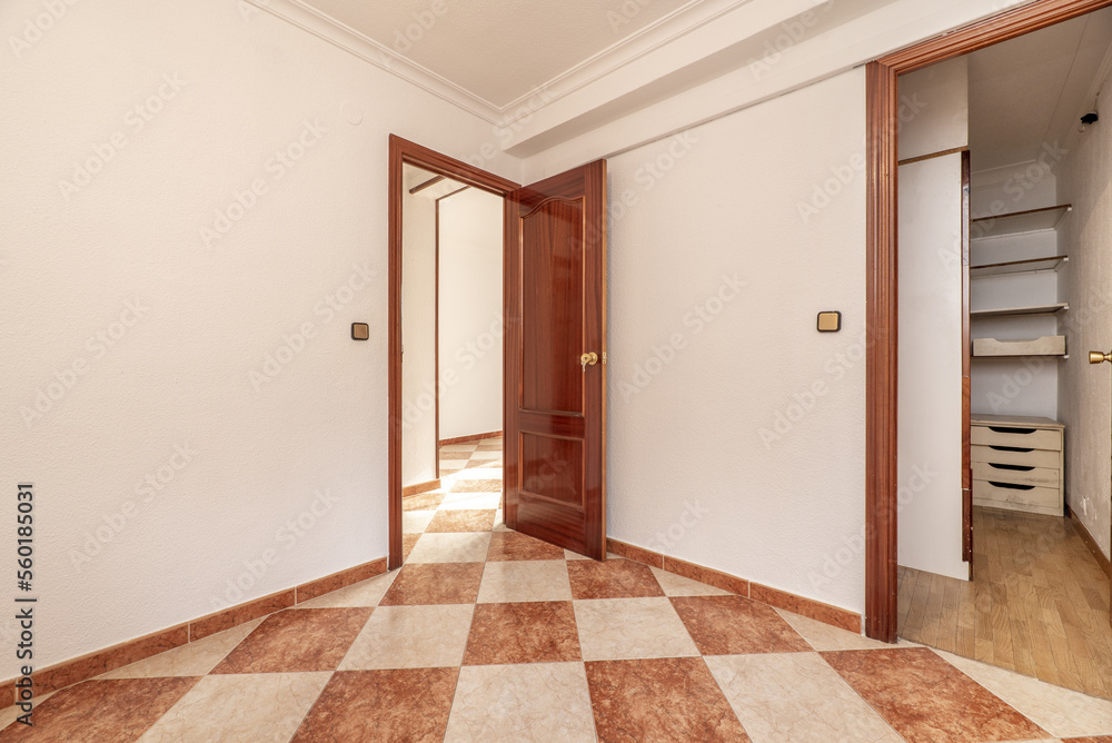 Empty room with white painted walls, checkered stoneware floors, sapele carpentry, a walk-in closet with wooden floors Empty room with white painted walls, checkered stoneware floors, sapele carpentry, a walk-in closet with wooden floors