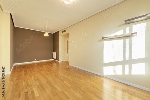 Empty living room with oak hardwood flooring, dark gray painted wall and two others in soft cream color