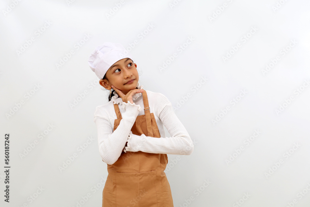 Thoughtful asian little girl in chef uniform thinking while looking sideways on empty space. Isolated on white background Thoughtful asian little girl in chef uniform thinking while looking sideways on empty space. Isolated on white background