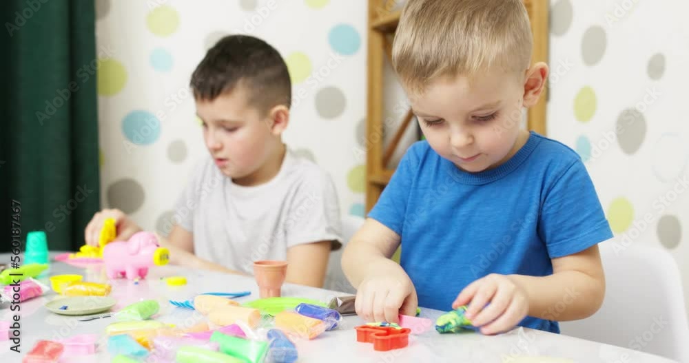 Cute children sitting at the table and plays with playdough Cute children sitting at the table and plays with playdough