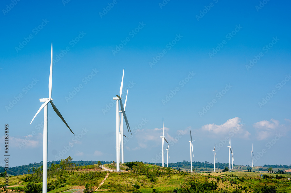 Wind turbines on beautiful sunny summer autumn mountain landsape. Curvy road through mountain. Green ecological power energy generation. Wind farm eco field