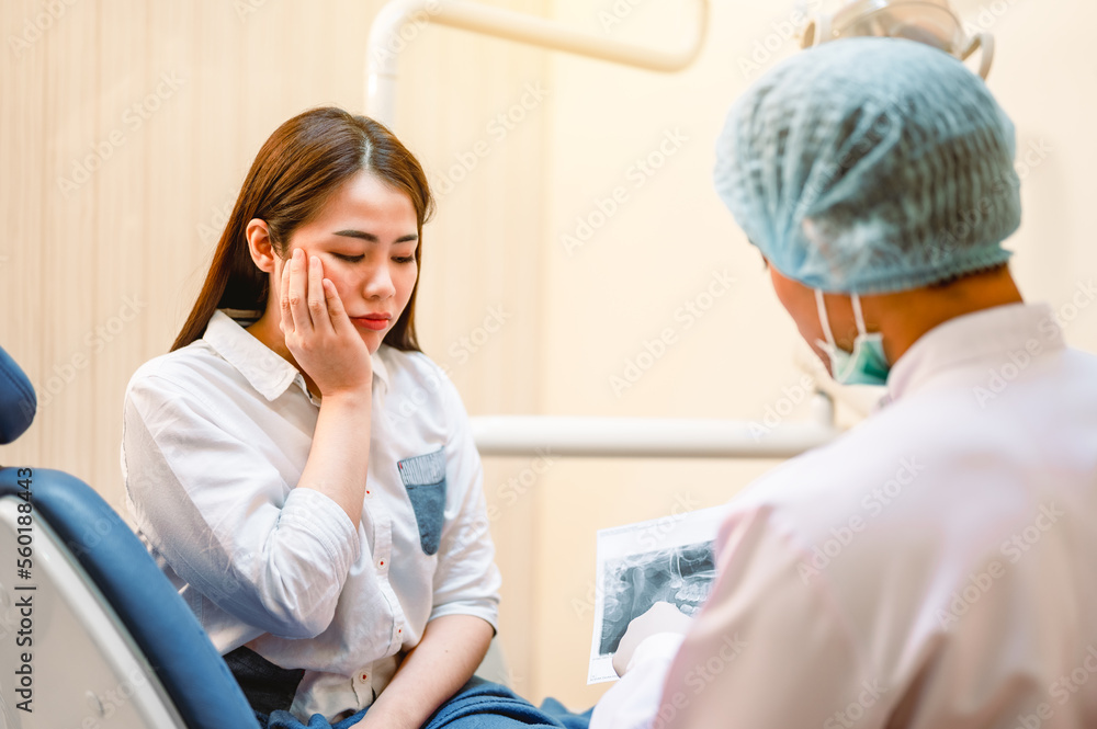The dentist is looking at the patient's dental x-ray results for an effective treatment and improves.she felt a toothache.The patient's dental health and a bright smile. The dentist is looking at the patient's dental x-ray results for an effective treatment and improves.she felt a toothache.The patient's dental health and a bright smile.