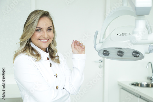 Mulher Dentista mostrando com sorriso os aparelhos utilizados.