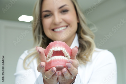 Mulher Dentista mostrando com sorriso os aparelhos utilizados. photo