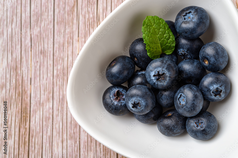 Ripe blueberry in white bowl over wooden surface. Juicy wild berry for vitamin vegan snack. Sweet blueberries vegetarian dessert. Detox diet raw ingredient. Horizontal frame. Ripe blueberry in white bowl over wooden surface. Juicy wild berry for vitamin vegan snack. Sweet blueberries vegetarian dessert. Detox diet raw ingredient. Horizontal frame.