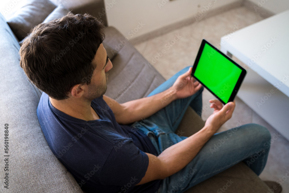 young man using a green screen tablet while working from home living room young man using a green screen tablet while working from home living room