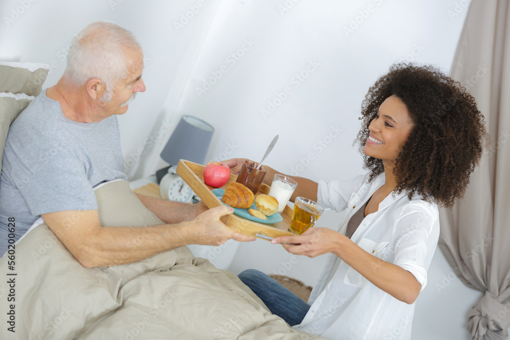 nurse serving breakfast to senior man in bedroom nurse serving breakfast to senior man in bedroom