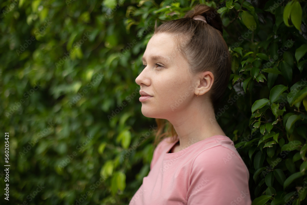 Portrait of a beautiful young woman standing on an Ivy wall or in greenery, smiling and looking away against from plant, girl relaxing outdoors during a sunny summer day. Love for nature, eco life Portrait of a beautiful young woman standing on an Ivy wall or in greenery, smiling and looking away against from plant, girl relaxing outdoors during a sunny summer day. Love for nature, eco life
