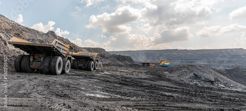 Panoramic view of coal mine. Open pit mine industry, big yellow mining truck for coal quarry. Open coal mining anthracite mining. Pit on coal mining by open way. Rock loading in trucks. Large truck photo