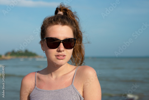 portrait young beautiful girl in sunglasses, on background embankment with sea, ocean and island view, smiling, relaxing, with closed eyes, sunset