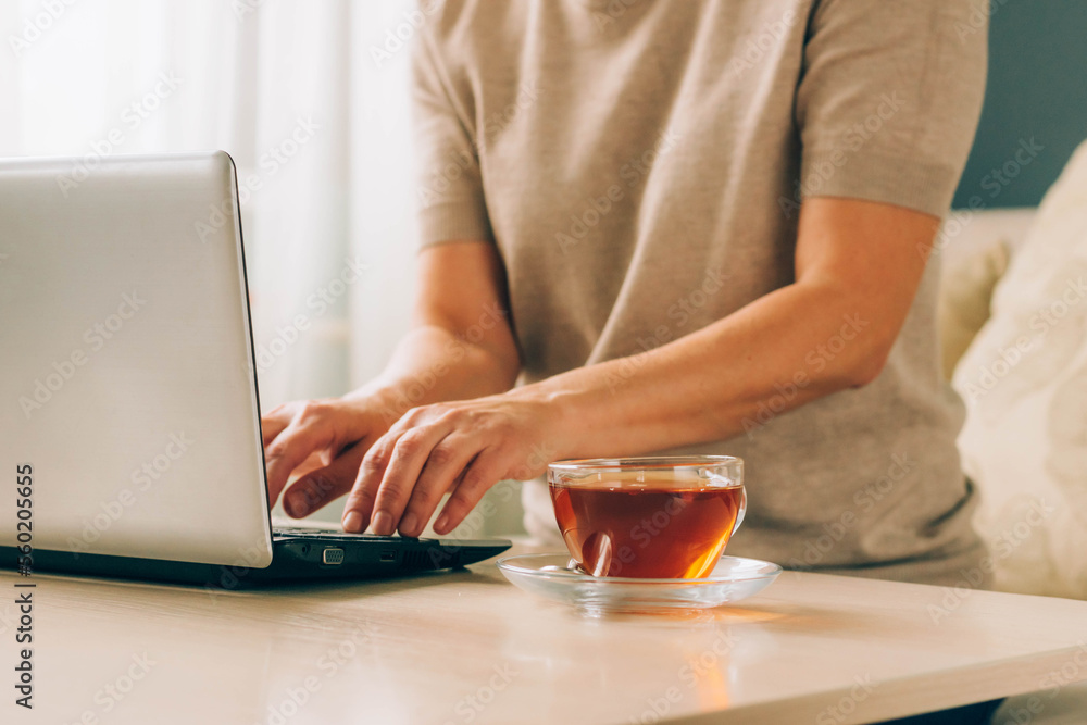Woman freelancer at home workplace laptop, cup of tea. Concept of distance learning, online work Woman freelancer at home workplace laptop, cup of tea. Concept of distance learning, online work