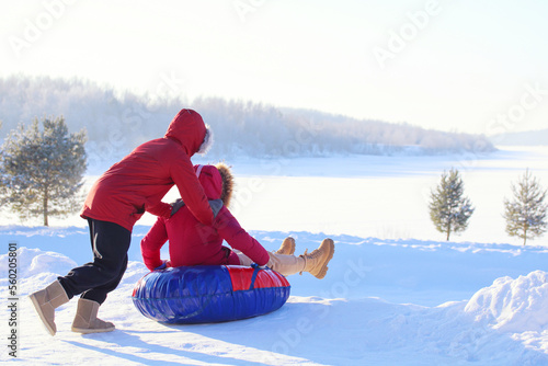 Vászonkép Teenagers in red jackets ride a winter tubing from a snow slide.