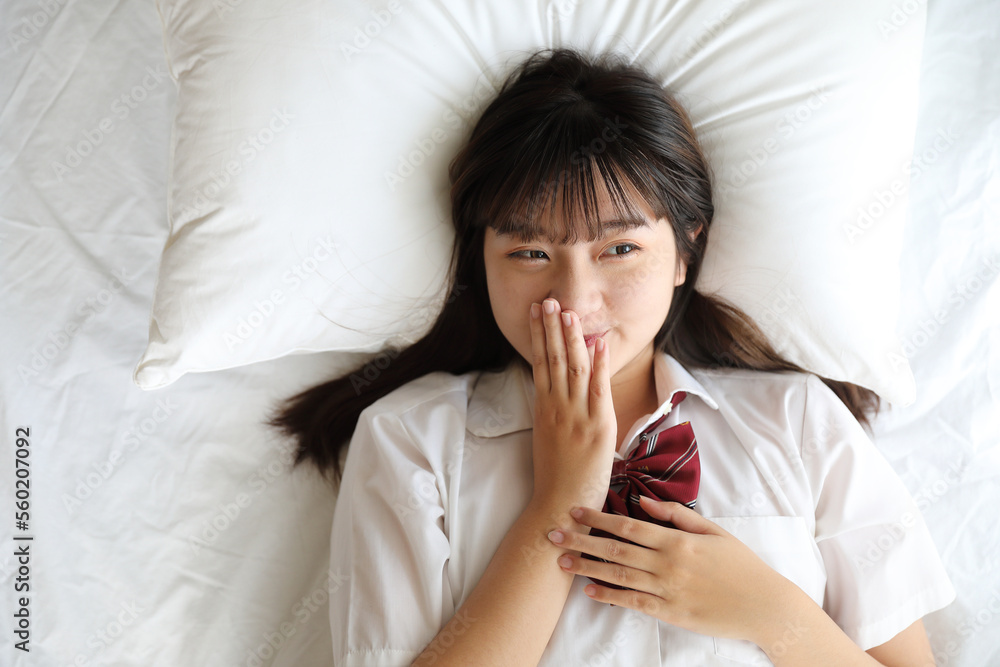 Portrait japanese school girl uniform sleep and look at camera in white tone bed room Portrait japanese school girl uniform sleep and look at camera in white tone bed room