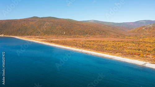 Autumn aerial photograph of the sea coast. Top view of the sea bay, beach and mountains. Sunny weather. Sea of Okhotsk. Nature of the Magadan region and Siberia. Journey to the Far East of Russia.