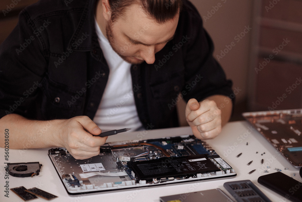 Disassembling a laptop with a screwdriver in a repair shop. 