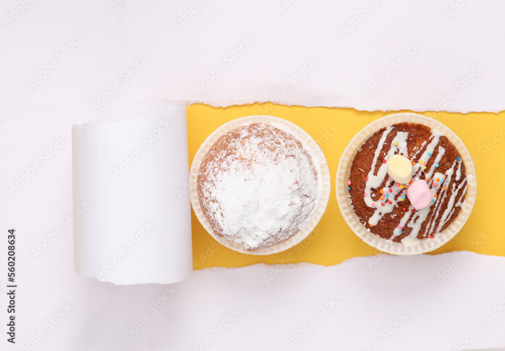 Two muffins against a yellow background with torn paper Two muffins against a yellow background with torn paper