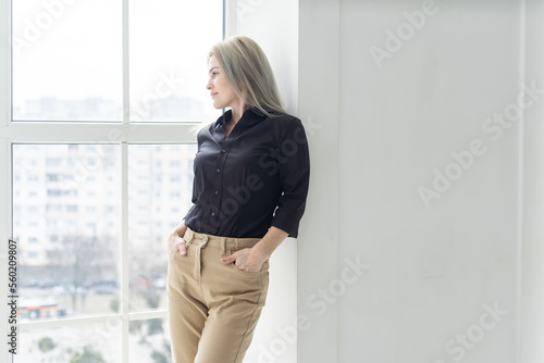 Young business woman wearing suite standing near window. Free Download Young business woman wearing suite standing near window. - GFXLoad