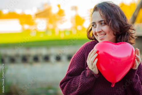Quadro su tela Mujer joven de raza caucásica sonriendo con un globo rojo con forma de corazón en las manos que le ha regalado su enamorado por el día de San valentín