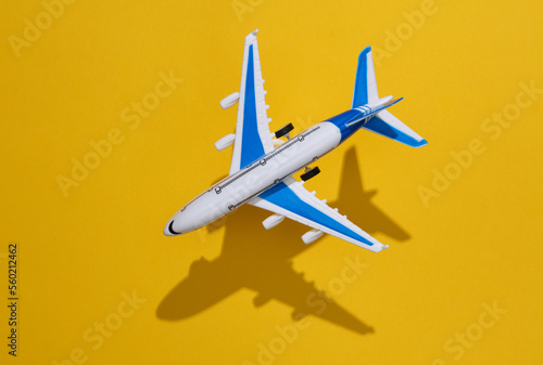 Toy plane flying on a yellow background with a shadow. Travel concept. Top view