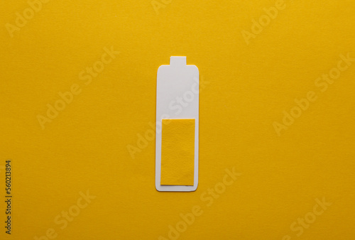 Paper-cut battery with an average charge level on a yellow background