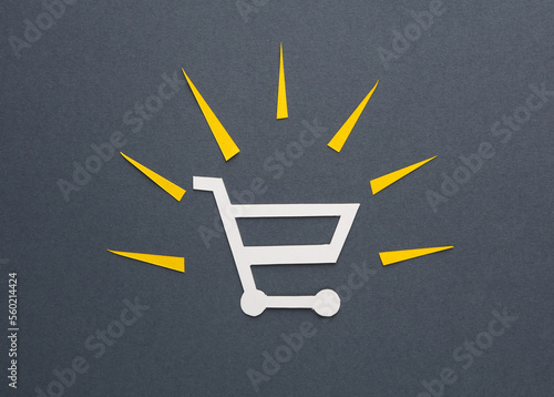 Shopping trolley with rays of light cut out of paper on a gray background