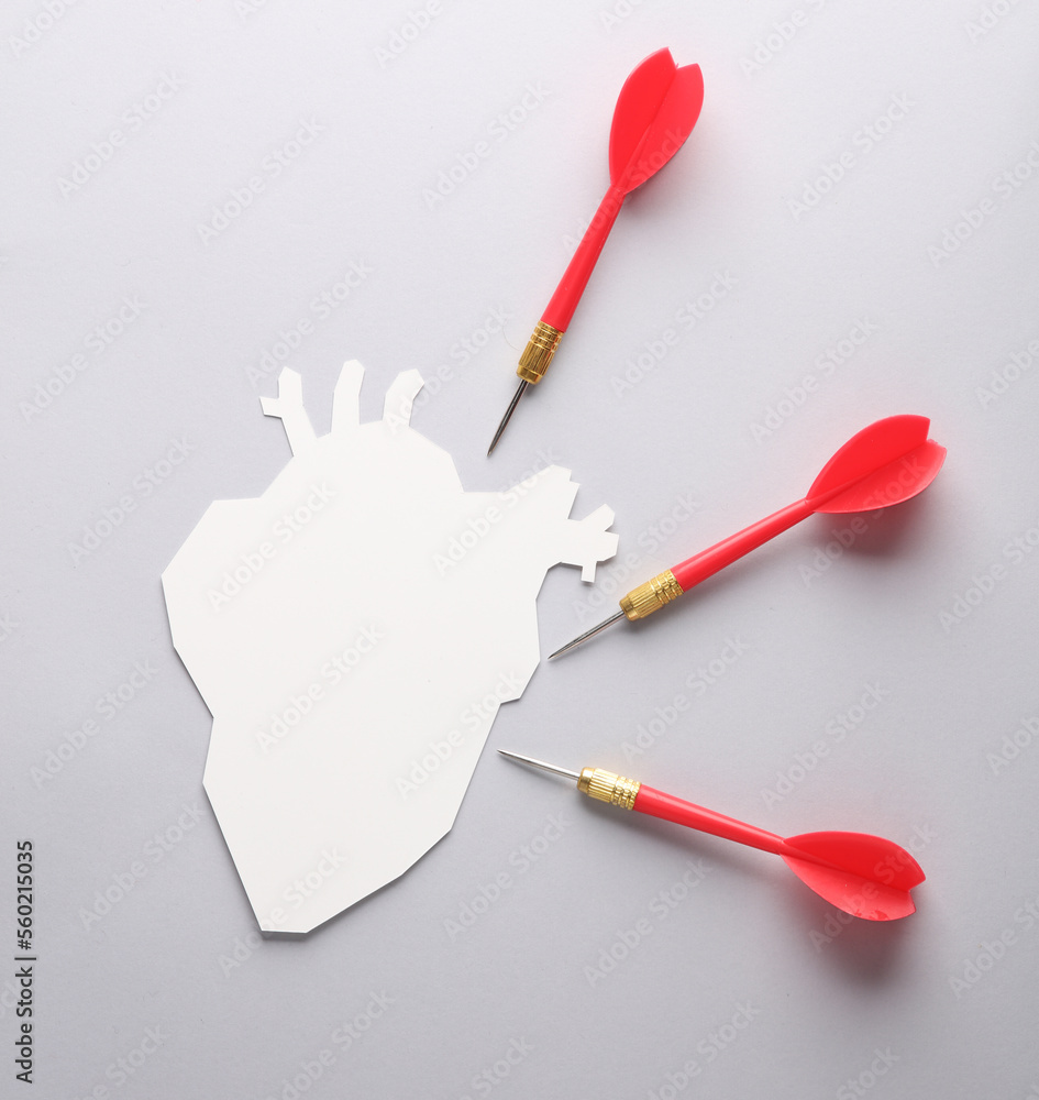 Paper-cut silhouette of a heart with darts on a gray background. Heart attack Paper-cut silhouette of a heart with darts on a gray background. Heart attack