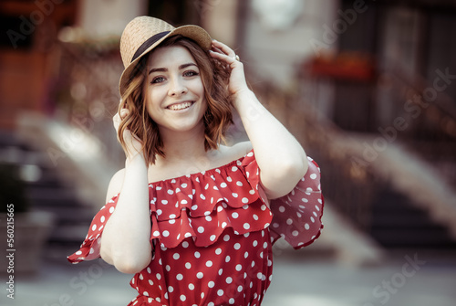 Portrait of a beautiful woman in a red polka dot dress and hat in the city