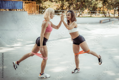 Two athletic female friends working out  high-five together outdoors