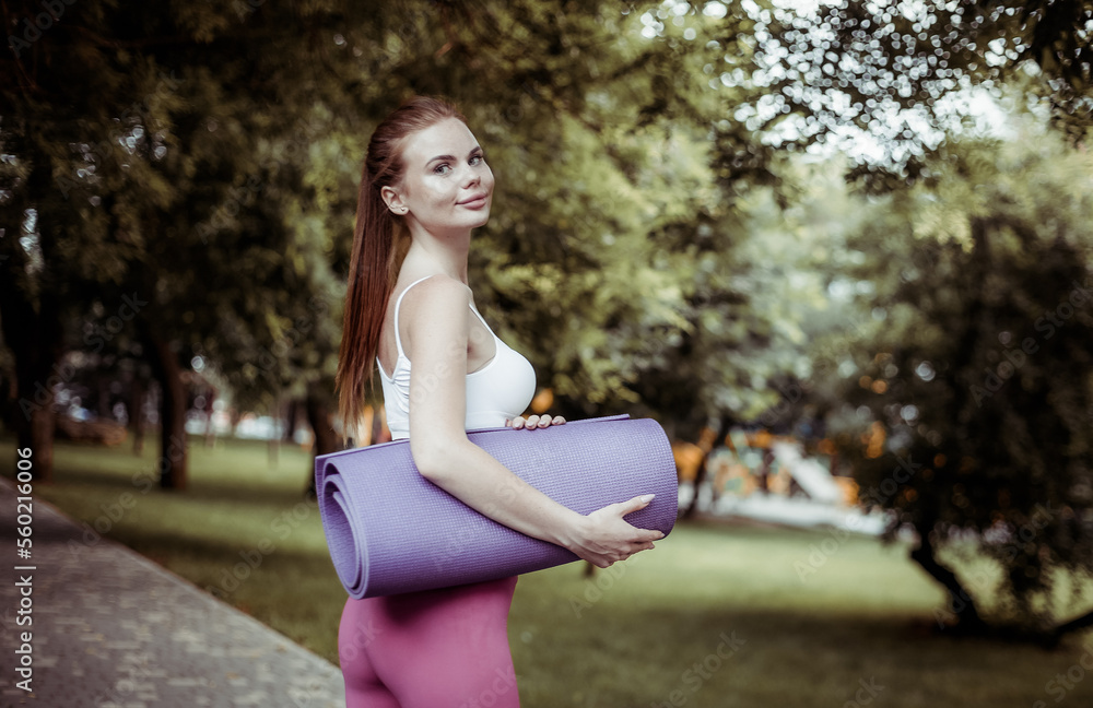 Healthy lifestyle concept. Red-haired happy woman fitness model in sportswear in the park