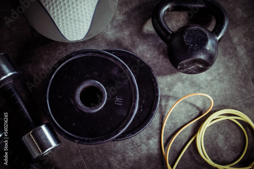Metal dumbbells, barbell discs, kettlebell, skipping rope and medicine ball on the gym floor. Fitness, bodybuilding and functional training equipment