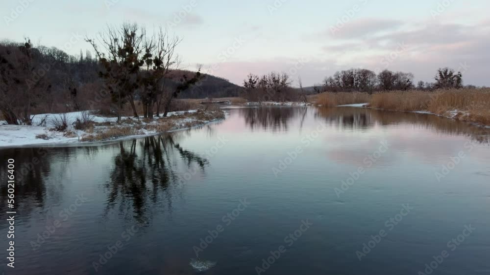 Winter evening river aerial with trees on snowy coast and evening cloudy sky reflection on water. Zmiyevsky region on Siverskyi Donets River, Ukraine Winter evening river aerial with trees on snowy coast and evening cloudy sky reflection on water. Zmiyevsky region on Siverskyi Donets River, Ukraine