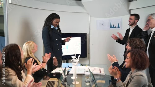 Elegant african woman talking in a meeting and business people clapping hands.