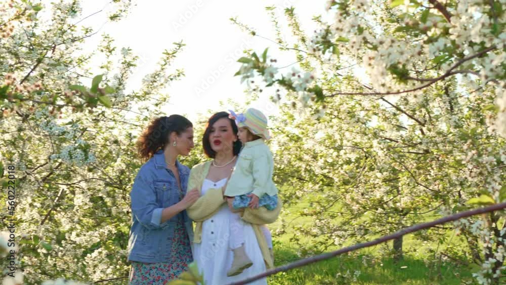 two attractive women with a little girl in their hands in a spring garden. two attractive women with a little girl in their hands in a spring garden.