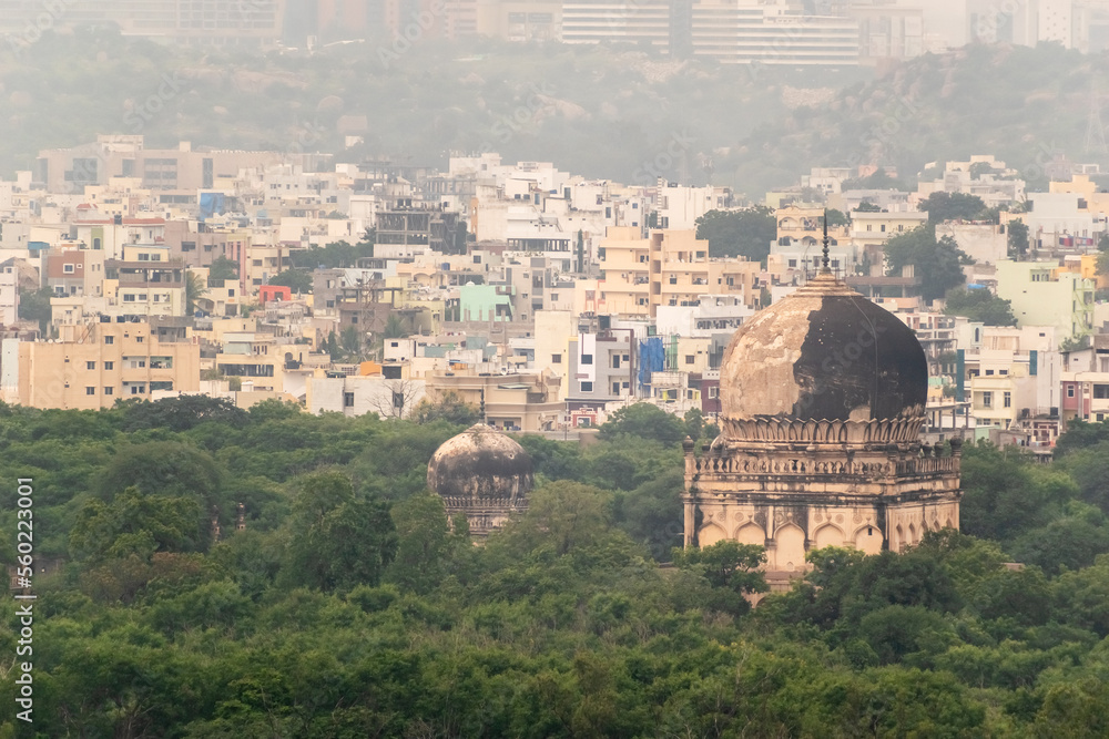 A congested cityscape of modern Hyderabad with the Qutb Shahi tombs in the foreground.