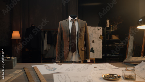 Mannequin with tailored shirt, tie and jacket in luxury designer atelier or tailoring studio. Table with tools, drawings and sketches of future clothes. Fashion, hand craft and couturier concept. photo