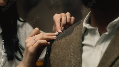Female seamstress works on business or wedding suit. African merican businessman ordering tailored jacket in stylish luxury designer atelier. Concept of fashion and hand craft. Close-up shot.